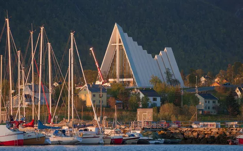 Segelboote vor einer modernen Kirche mit spitzem Dach in einer malerischen Landschaft.