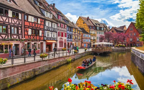 Bunte Fachwerkhäuser und ein Kanal mit Boot in einer europäischen Altstadt.