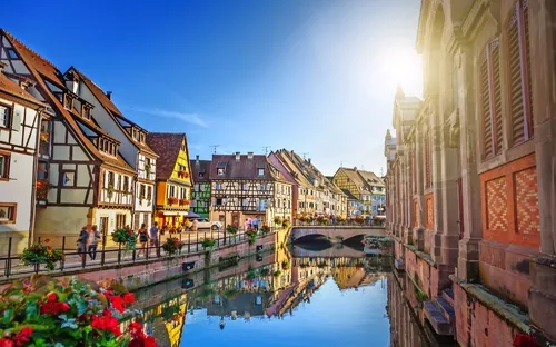 Fachwerkhäuser und Kanal in malerischer Altstadt bei Sonnenuntergang.