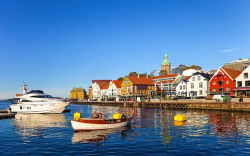 Boote im Hafen vor bunten Häusern und einer Kirche bei sonnigem Wetter
