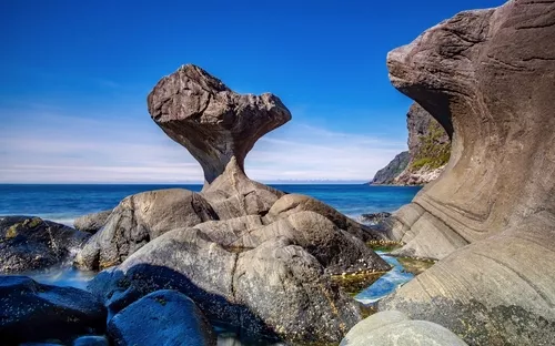 Felsformationen am Meer unter blauem Himmel.