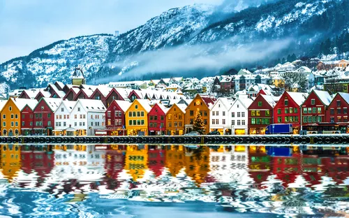 Bunte Häuserzeile in Bergen, Norwegen, mit Schneebedeckten Bergen im Hintergrund.
