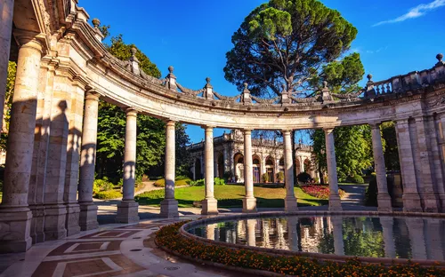 Historischer Säulengang mit Rundbogen und Wasserbecken im Sonnenschein.