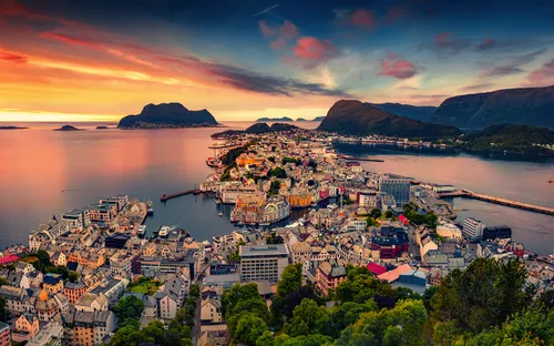 Küstenstadt bei Sonnenuntergang mit Bergen und Meer im Hintergrund