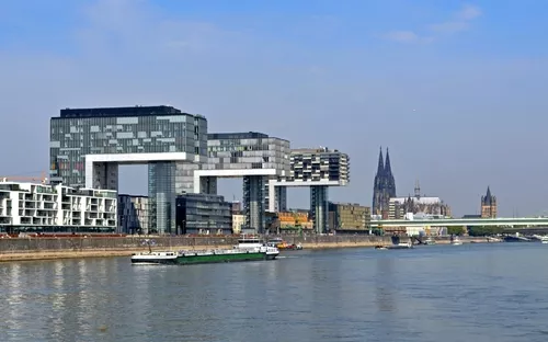 Kranhäuser am Rhein in Köln mit dem Kölner Dom im Hintergrund bei klarem Himmel.