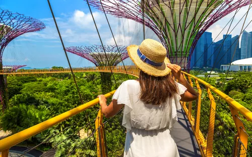 Frau mit Strohhut auf einem Gehweg in SuperTree Grove, Singapur.
