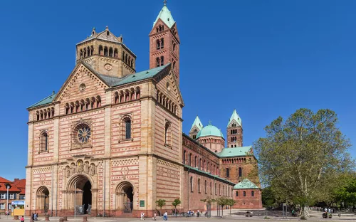 Romanische Kathedrale mit markantem Turm und blauem Himmel im Hintergrund.