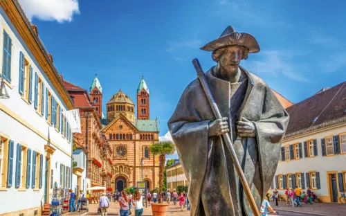 Statue eines Pilgers vor dem Speyerer Dom an einem sonnigen Tag.