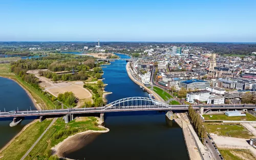 Luftaufnahme einer Stadt mit Fluss, Brücke und grünen Landschaften.