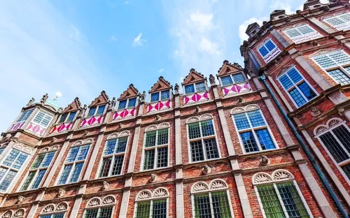 Fassade eines historischen Gebäudes mit verzierten Fenstern und Backsteinmauern.