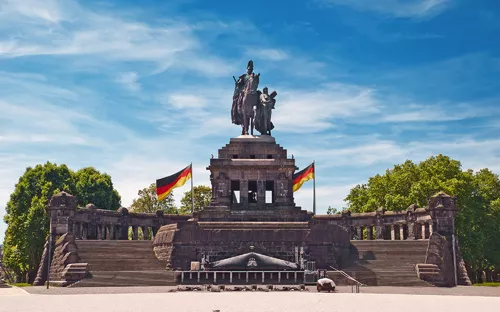 Denkmal mit Reiterstatue, deutscher Fahne und blauem Himmel im Hintergrund.