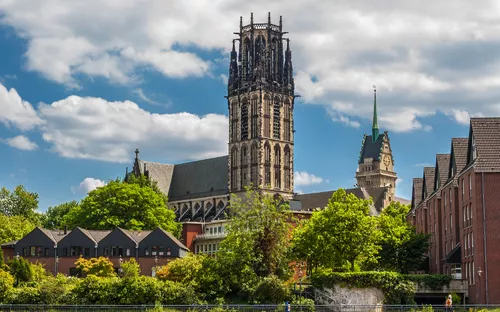 Große Kirche mit hohem Turm vor blauem Himmel und Wolken.