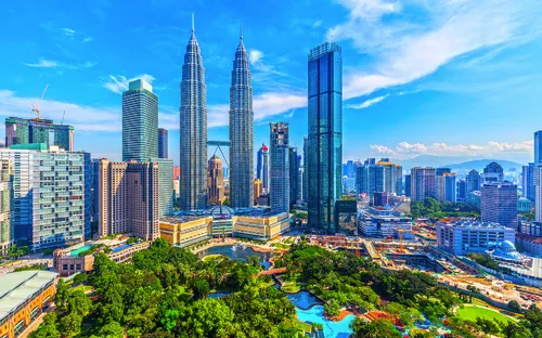 Stadtblick auf Kuala Lumpur mit Petronas Towers und Parks bei klarem Himmel.