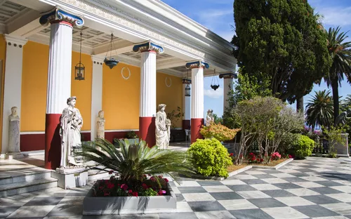 Klassischer Säulengang mit Statuen und Pflanzen im Garten.