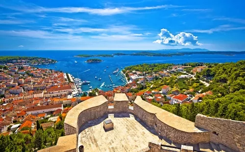 Aussicht auf Küstenstadt mit rotem Dach und blauem Meer im Hintergrund.