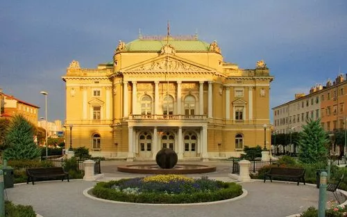 Historisches Gebäude mit beeindruckender Fassade und Garten im Vordergrund.