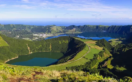 Panoramaansicht von grünen Hügeln und Kraterseen unter blauem Himmel.