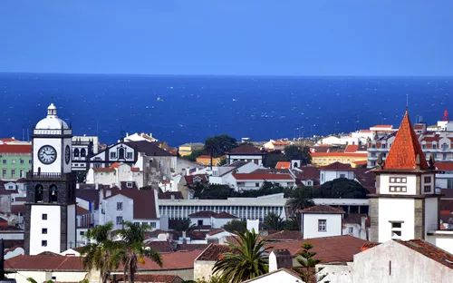 Stadtansicht mit Kirchturm und Meer im Hintergrund.