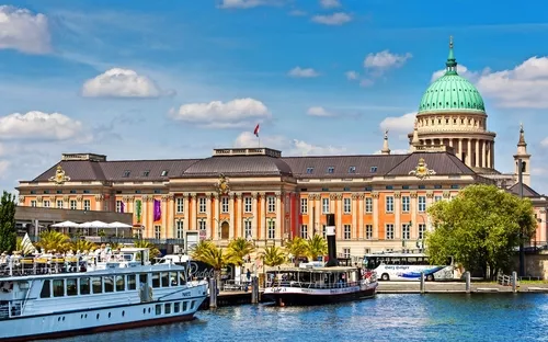 Historisches Gebäude am Wasser mit Booten im Vordergrund.
