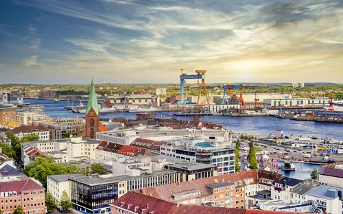 Luftaufnahme von Kiel mit Hafen und Stadtansicht bei Sonnenuntergang.