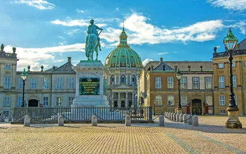 Reiterstatue vor einem historischen Gebäudeensemble bei Sonnenschein.