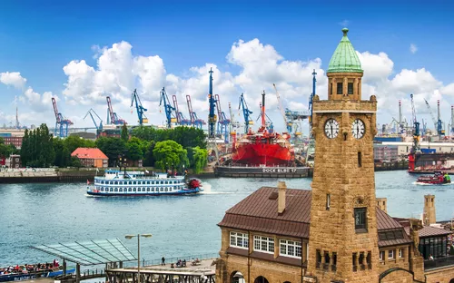 Hafenansicht mit Turm und Schiff vor blauem Himmel im Hintergrund.