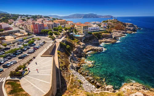 Küste und Hafenstadt in Calvi, Korsika, Frankreich mit bunten Gebäuden und klarem blauen Meer.