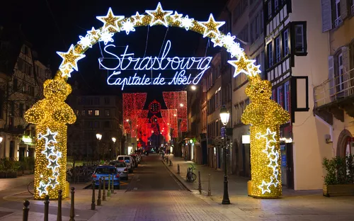 Festlich beleuchteter Torbogen in Straßburgs Altstadt bei Nacht.