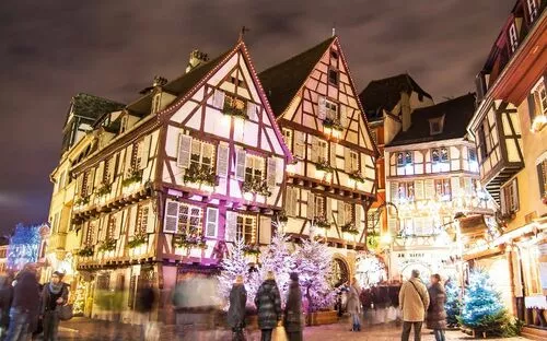 Fachwerkhäuser auf einem festlich beleuchteten Weihnachtsmarkt.
