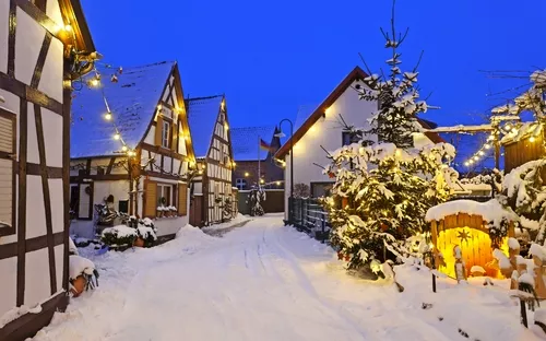 Verschneite Dorfstraße mit Fachwerkhäusern und weihnachtlicher Beleuchtung