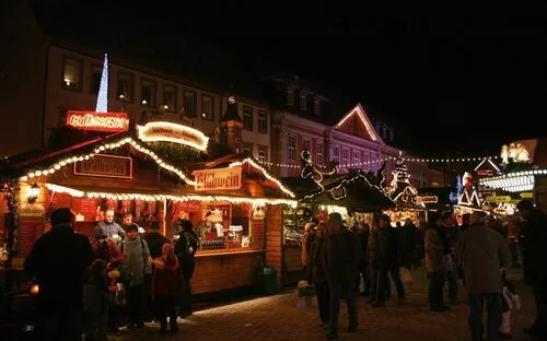 Besucher auf einem festlich beleuchteten Weihnachtsmarkt in Speyer bei Nacht.