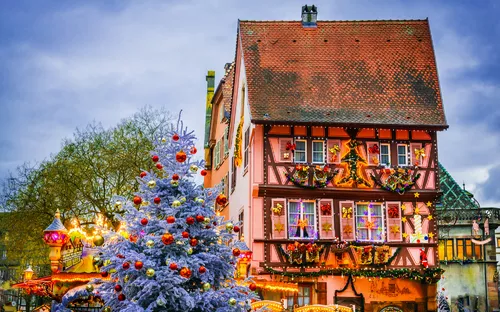 Fachwerkhaus mit Weihnachtsdekoration und geschmücktem Tannenbaum im Winter.