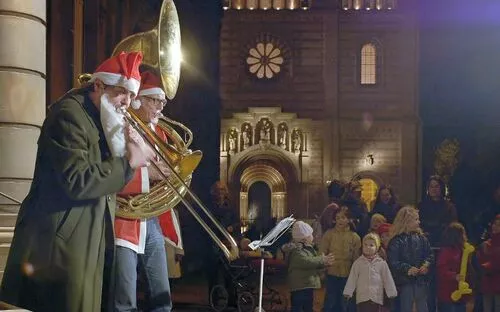 Weihnachtsmusikanten vor beleuchtetem Gebäude in Speyer bei Nacht.