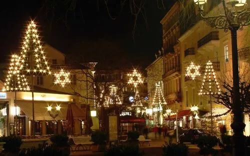 Straßenansicht mit weihnachtlicher Beleuchtung und geschmückten Bäumen bei Nacht.