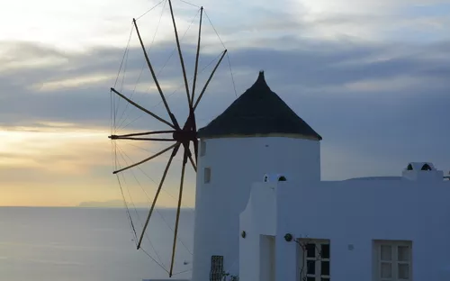 Windmühle im Dorf Oia auf der Insel Santorin in Griechenland mit Blick auf das Ägäische Meer.