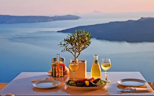 Tisch mit Abendessen und Wein mit Meerblick im Sonnenuntergang