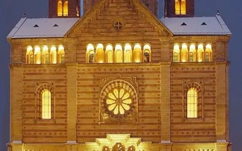 Ein beleuchteter Dom bei Nacht mit brennendem Weihnachtsbaum davor.