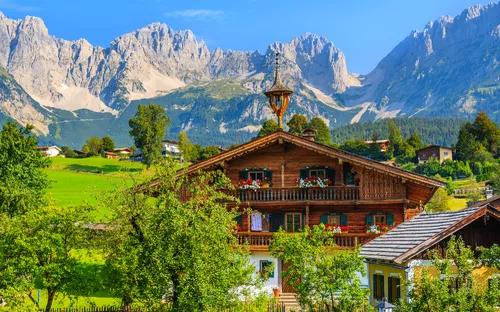 Traditionelles Almhaus in Going am Wilden Kaiser vor der Kulisse der Tiroler Alpen.
