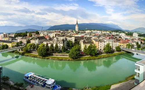Stadtansicht mit Fluss, Kirche und Boot im Vordergrund.