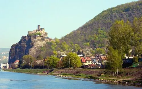 Burg Strekov auf einem Hügel über der Elbe, umgeben von Bäumen und Wohnhäusern.