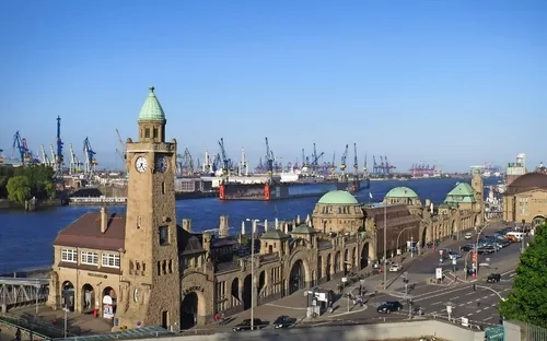 Landungsbrücken in Hamburg mit Hafen und blauem Himmel im Hintergrund.