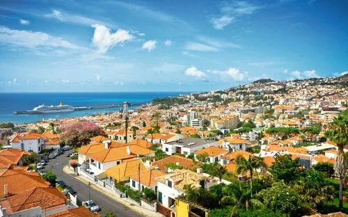 Panorama von Funchal auf Madeira mit roten Dächern und einem Kreuzfahrtschiff im Hafen.