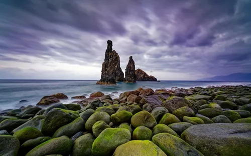 Küstenlandschaft mit Felsformationen im Meer und bewölktem Himmel.