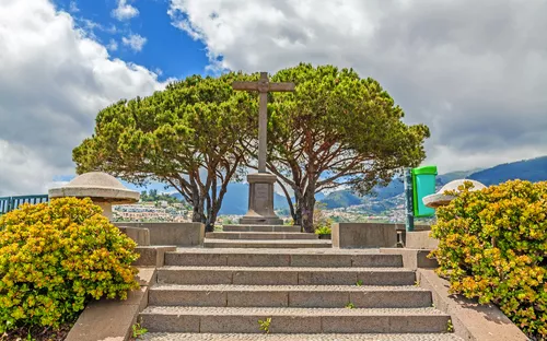 Aussichtspunkt Pico dos Barcelos in Funchal mit einem Kreuz und Bäumen im Hintergrund.