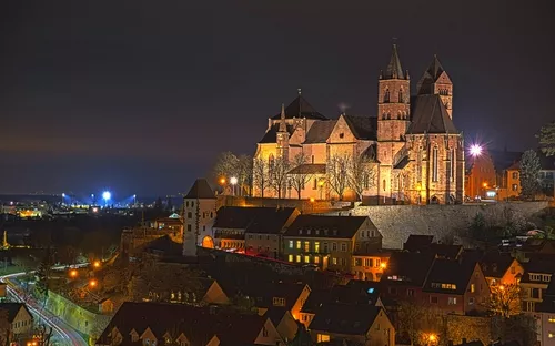 Nachtsicht auf das beleuchtete Stephansmünster in Breisach mit umliegenden Gebäuden.