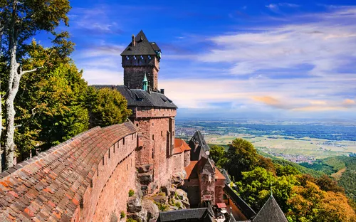 Burg mit Zinnen und Türmen auf Hügel mit Blick über die Landschaft bei klarem Himmel