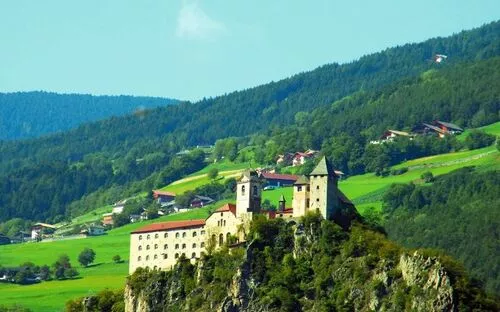 Kloster Säben auf einem Hügel mit grüner Landschaft im Hintergrund.