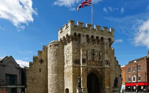 Historisches Steintor mit britischer Flagge und blauem Himmel.