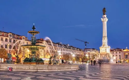 Brunnen und Säule auf einem Platz in einer Stadt bei Abenddämmerung.