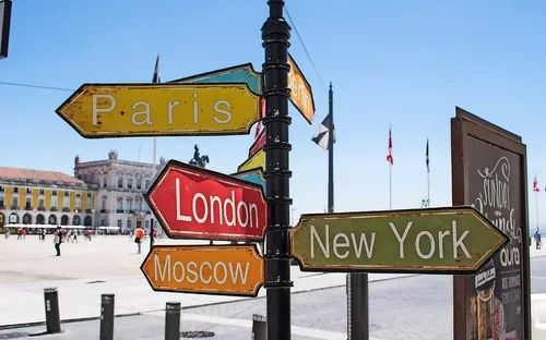 Wegweiser mit Schildern nach Paris, London, New York und Moskau auf einem Platz.